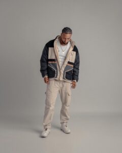Portrait of a man wearing a trendy jacket and cargo pants in a studio setting.